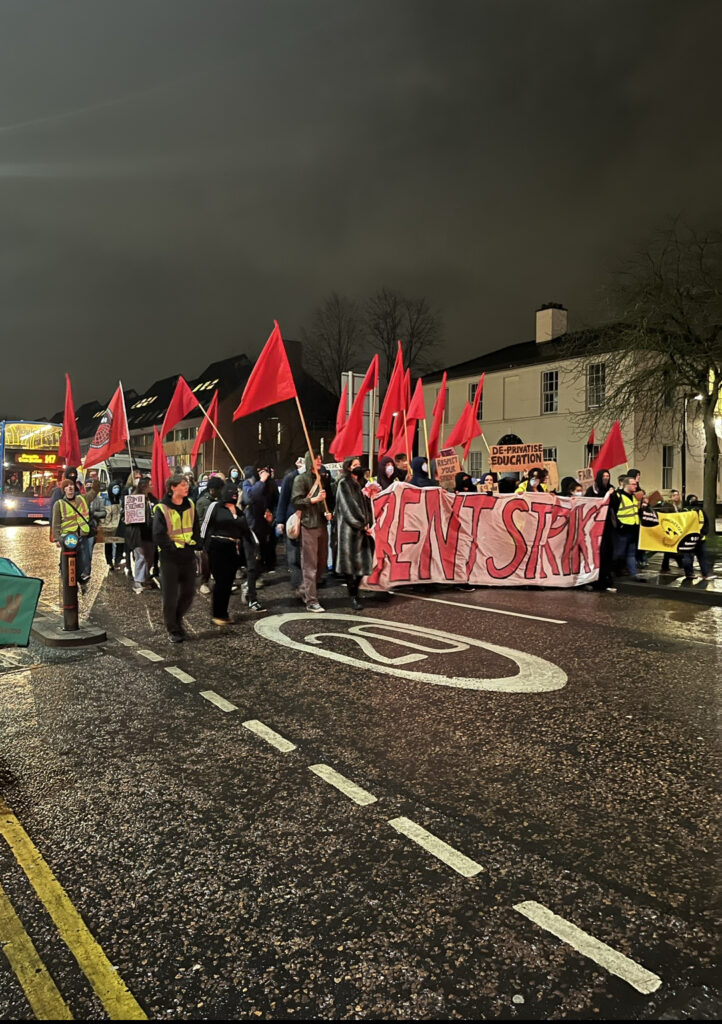 Rent strike students waving placards and banners march down Oxford Road