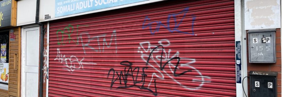 SASCA charity building in Moss Side with shutters closed, covered in graffiti