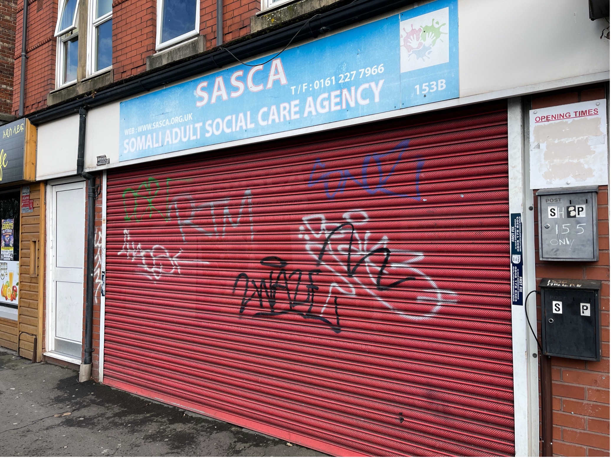 SASCA charity building in Moss Side with shutters closed, covered in graffiti