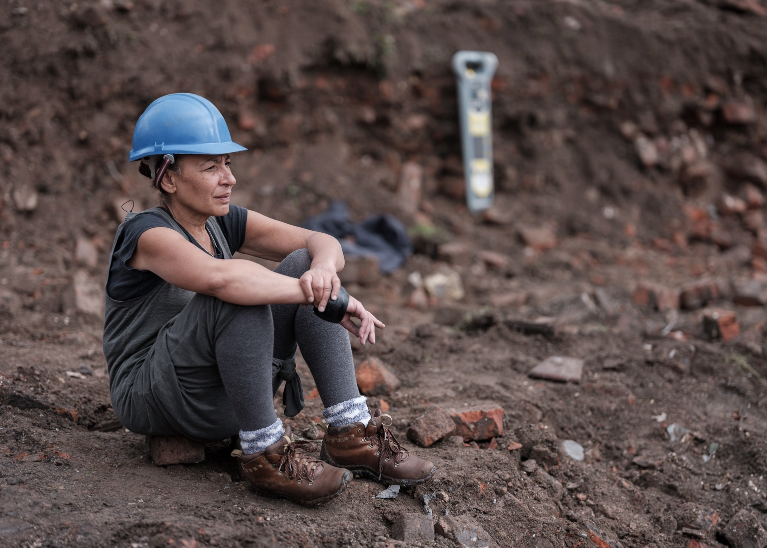 Linda Brogan sat on a brick in a builders hat at excavation of the Reno surrounded by rubble