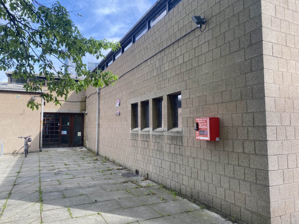 Brick walls with windows and a door and a red emergency bleed control box attached