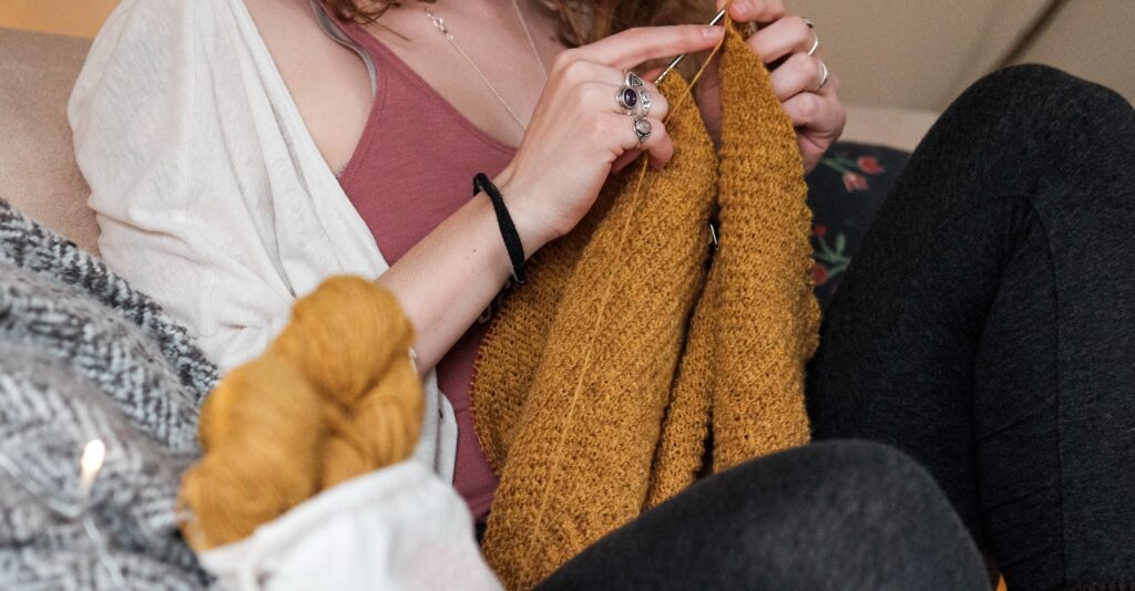 Woman siting down knitting a jumper