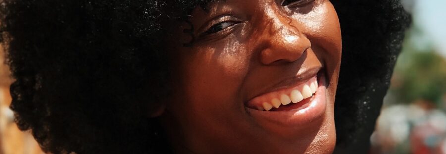 Black woman with think jet back hair, with a beautiful smile looking over her right shoulder