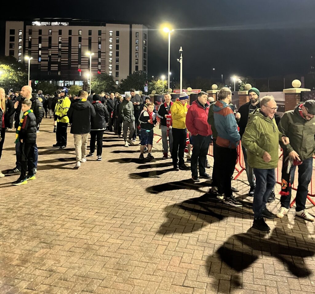 A line of people besides a red barricade.