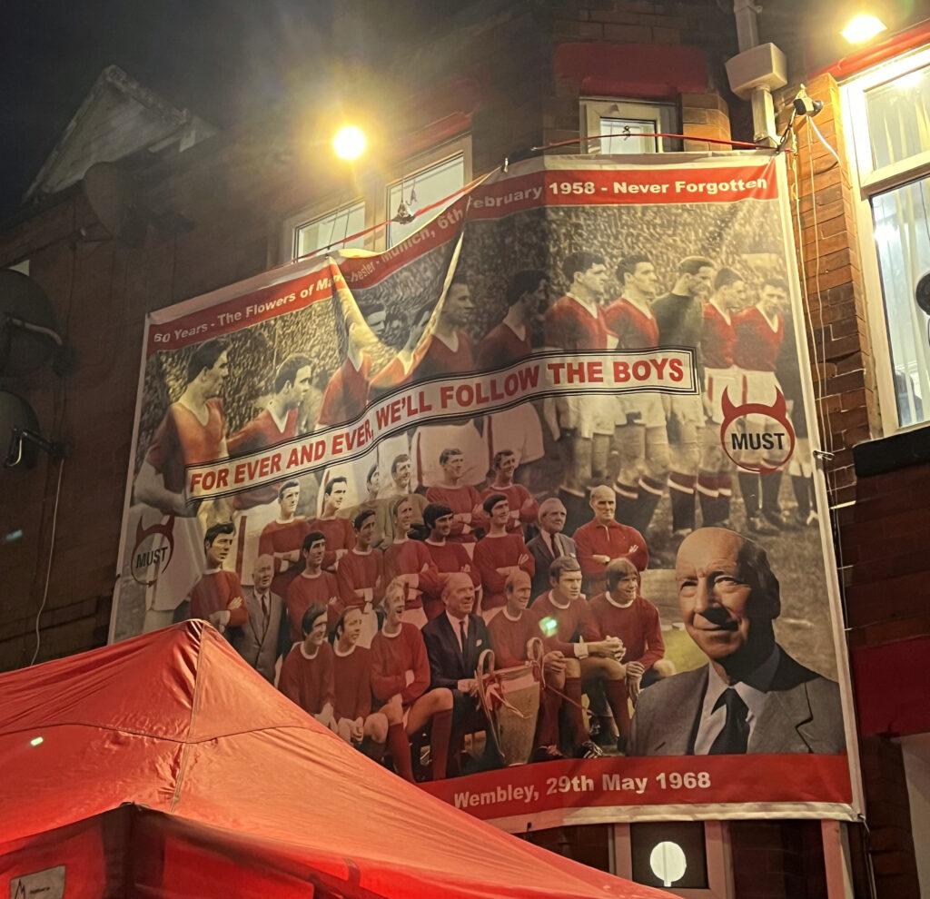 A mural to Sir Bobby Charlton and many other victims of the Munich air disaster, with the words 'FOREVER AND EVER, WE'LL FOLLOW THE BOYS' in the centre.