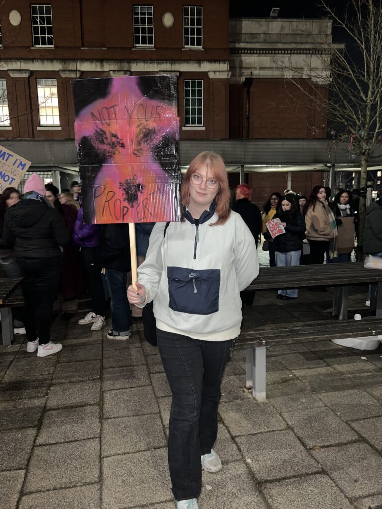 Phoebe Boniface shows off the sign she made, and expressed more needs to be done regarding women's safety. Her sign reads 'Not your property' .