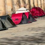 Four tents in St. Peter's Square, Manchester with support messages for a ceasefire chalked on the wall.