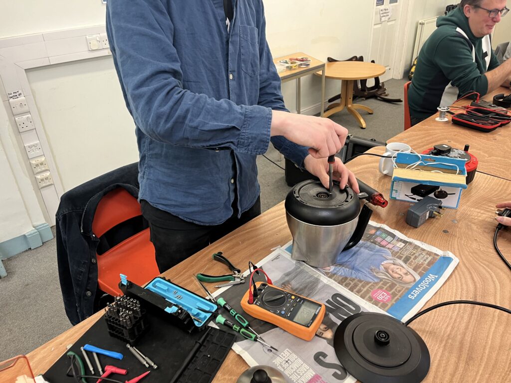 Image of a man repairing a kettle with a screwdriver