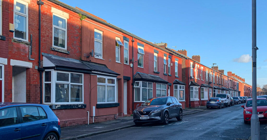 A row of terraced houses stretching into the distance. The weather is bright and sunny. There are no people in the picture. 