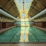 Withington Baths interior with pool and refurbished roof. Light reflects in pool water.