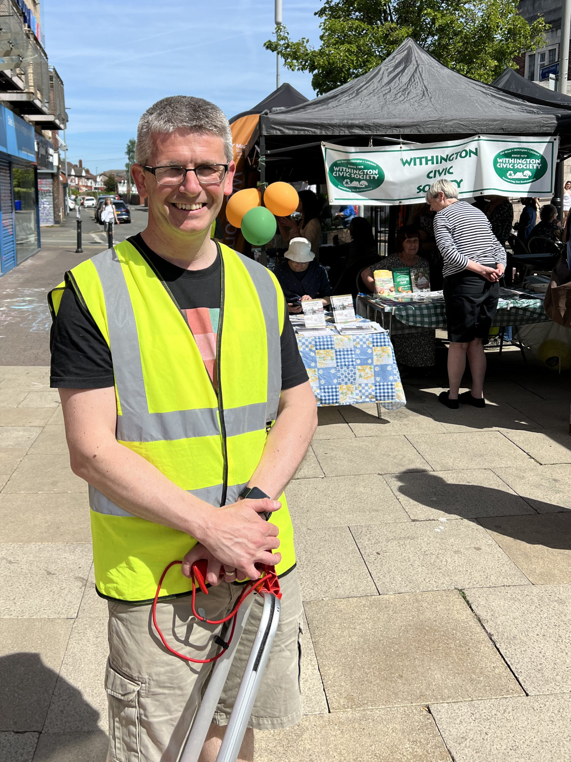 Local Councillor Gavin White litter picking in from of Withington Civic Society stall.