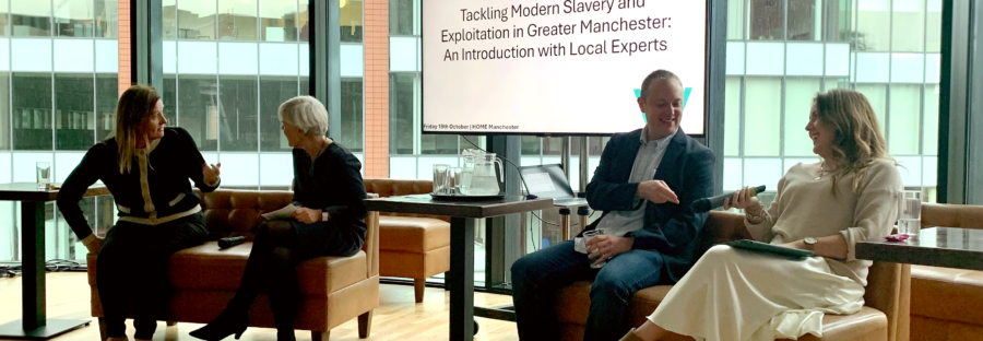 Three women and a man sit on two brown sofas in front of a digital whiteboard that reads: "Tackling Modern Slavery and Exploitation in Greater Manchester: An Introduction with Local Experts." They are sat in an open area with a glass wall behind them that faces the wall of another building. All four people are in conversation, and are well-dressed in business attire. There is a microphone on the left sofa, and the woman on the far-right of the image holds the other. In order, they are: local business lmanager Angela Hughes; Deputy Mayor of Manchester Kate Green; Dr Jon Davies from the University of Manchester; and Amy Bond from anti-slavery charity Causeway.