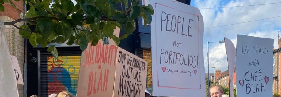 A group of people holding signs in front of Café Blah