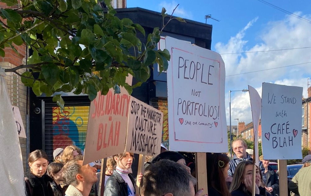 A group of people holding signs in front of Café Blah