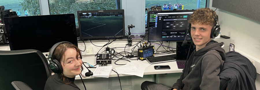 Two student journalists sat at a mixing desk for braodcasting sport from matchDay Live