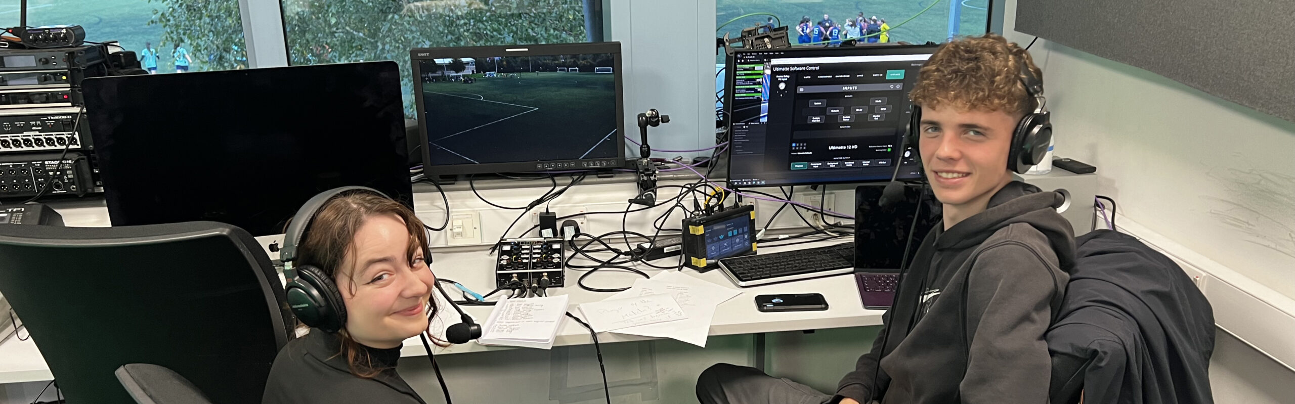 Two student journalists sat at a mixing desk for braodcasting sport from matchDay Live