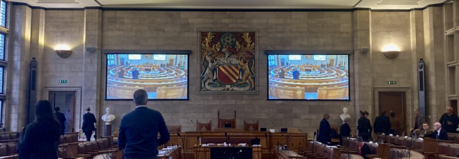 Councillors standing up from wooden benches and vacating Manchester City Council's second floor chamber