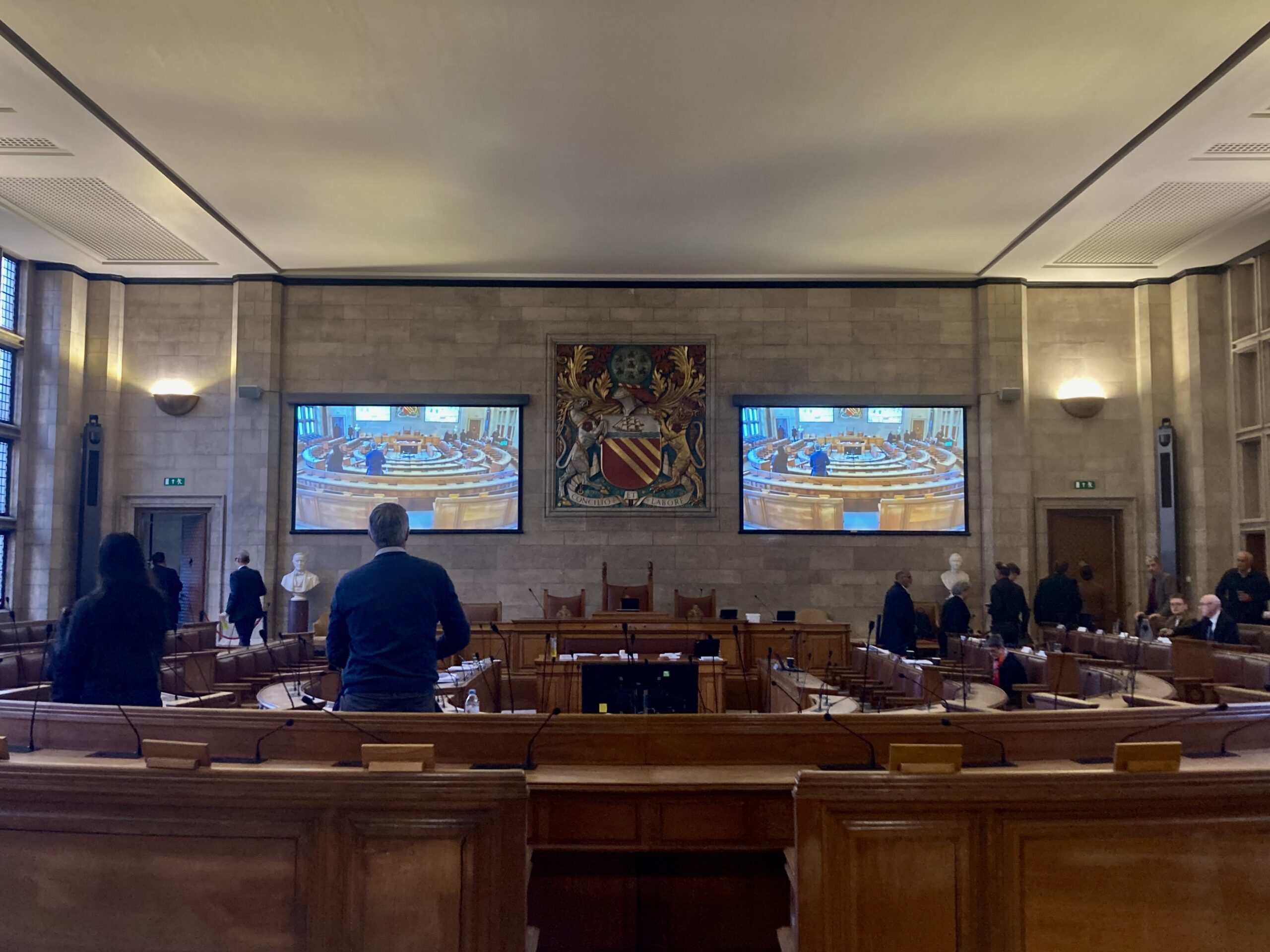 Councillors standing up from wooden benches and vacating Manchester City Council's second floor chamber