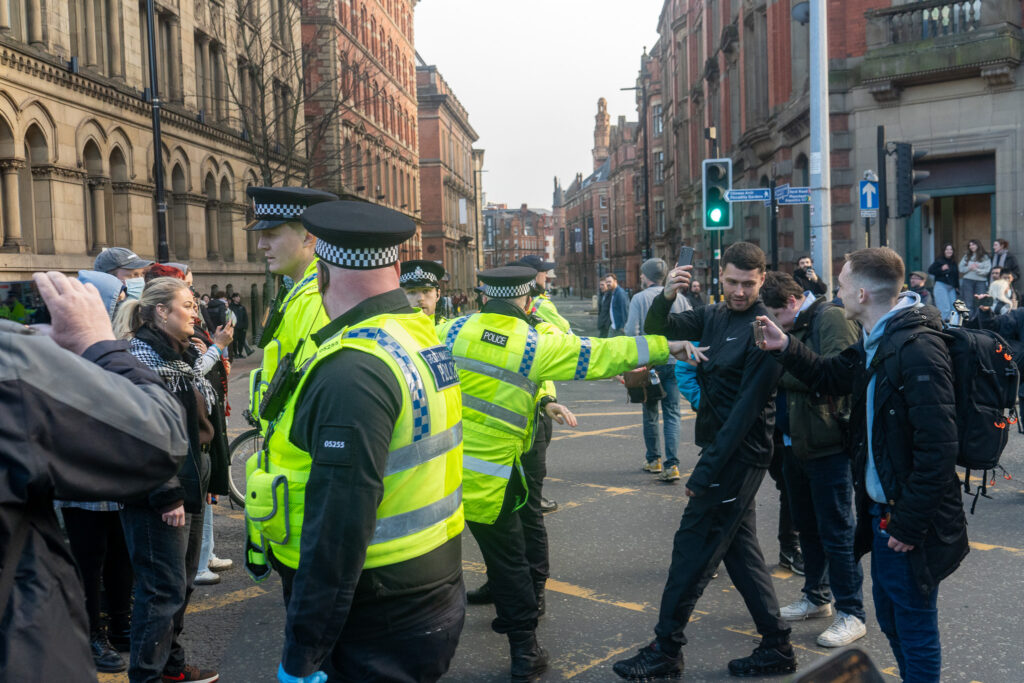 Officers wearing high-vis jackets hit out at a man in dark clothes.