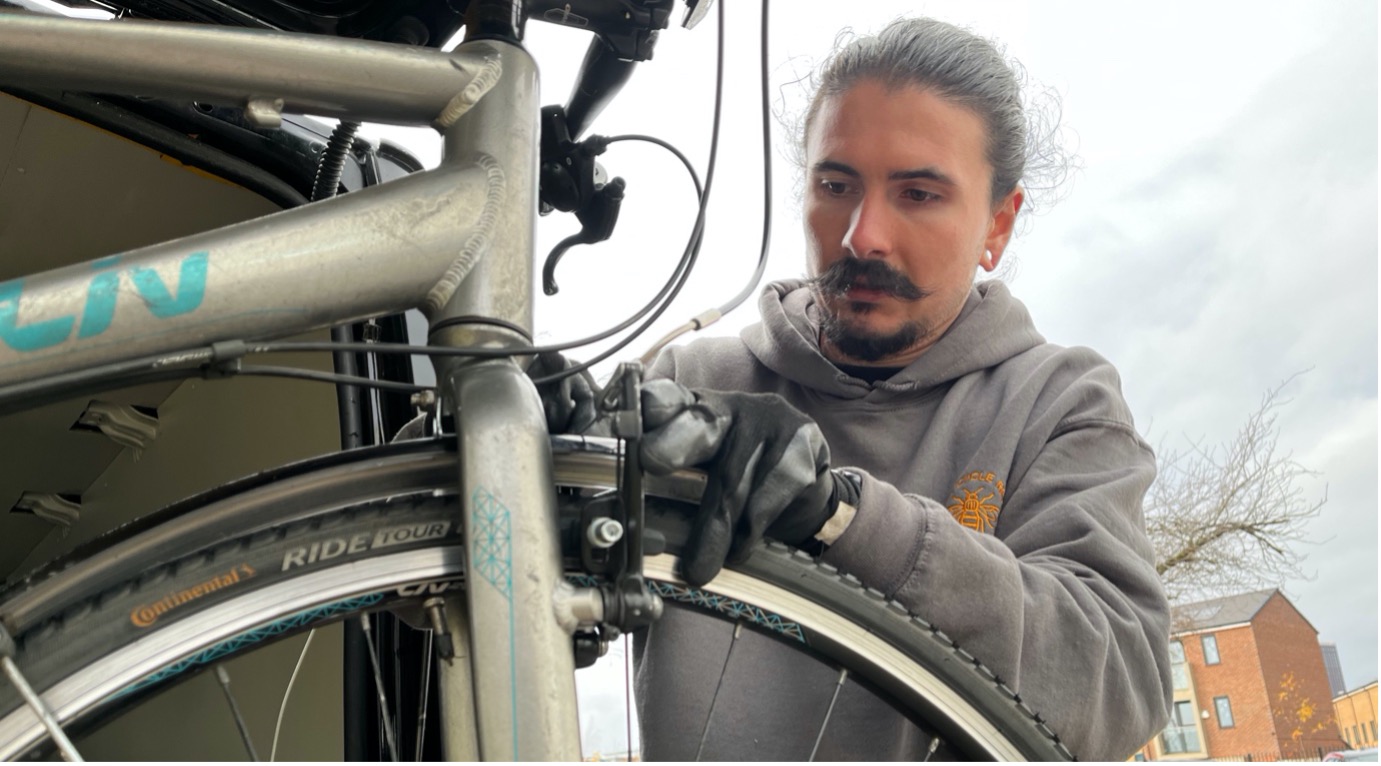 Joe Rostern repairs bike for bike libraries programme