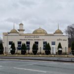 Beige coloured Mosque with gold accents, next to a road