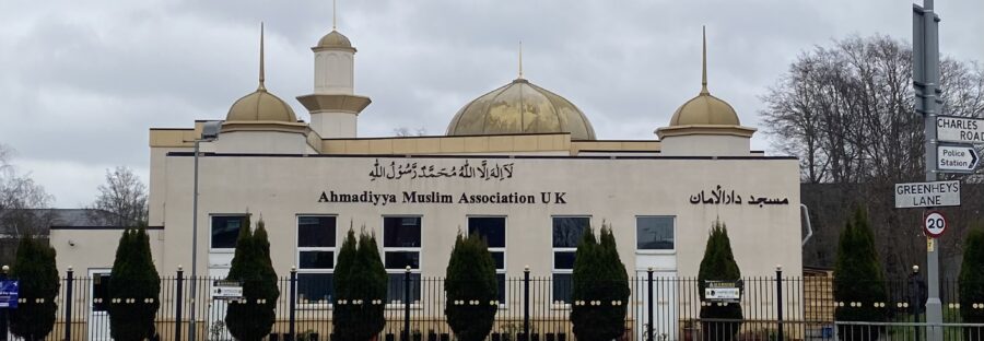 Beige coloured Mosque with gold accents, next to a road