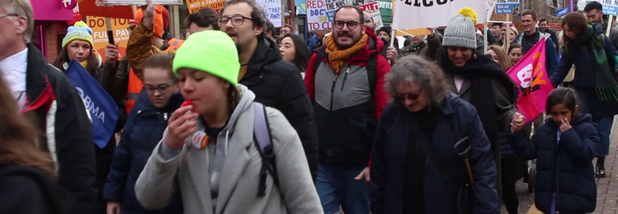 workers marching down Oxford Road during strike action for better pay.