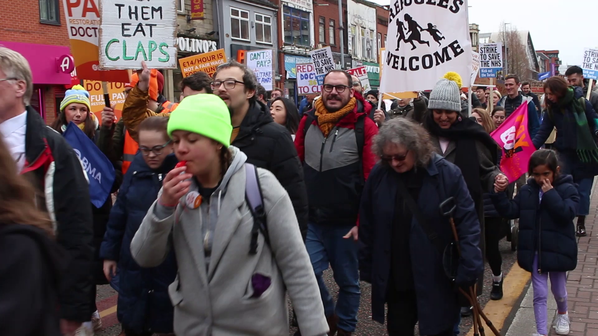 workers marching down Oxford Road during strike action for better pay.