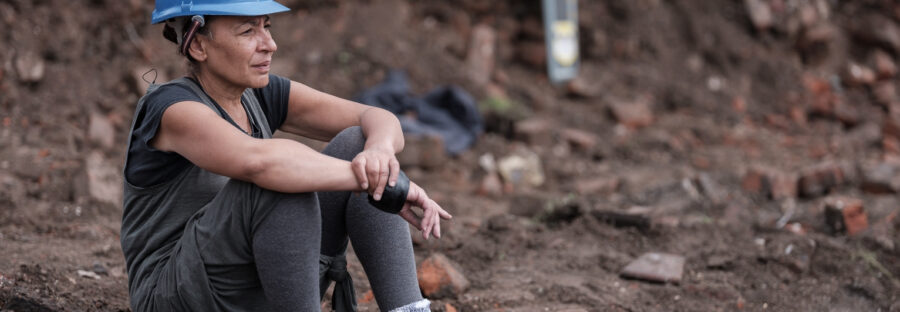 Linda Brogan sat on a brick in a builders hat at excavation of the Reno surrounded by rubble