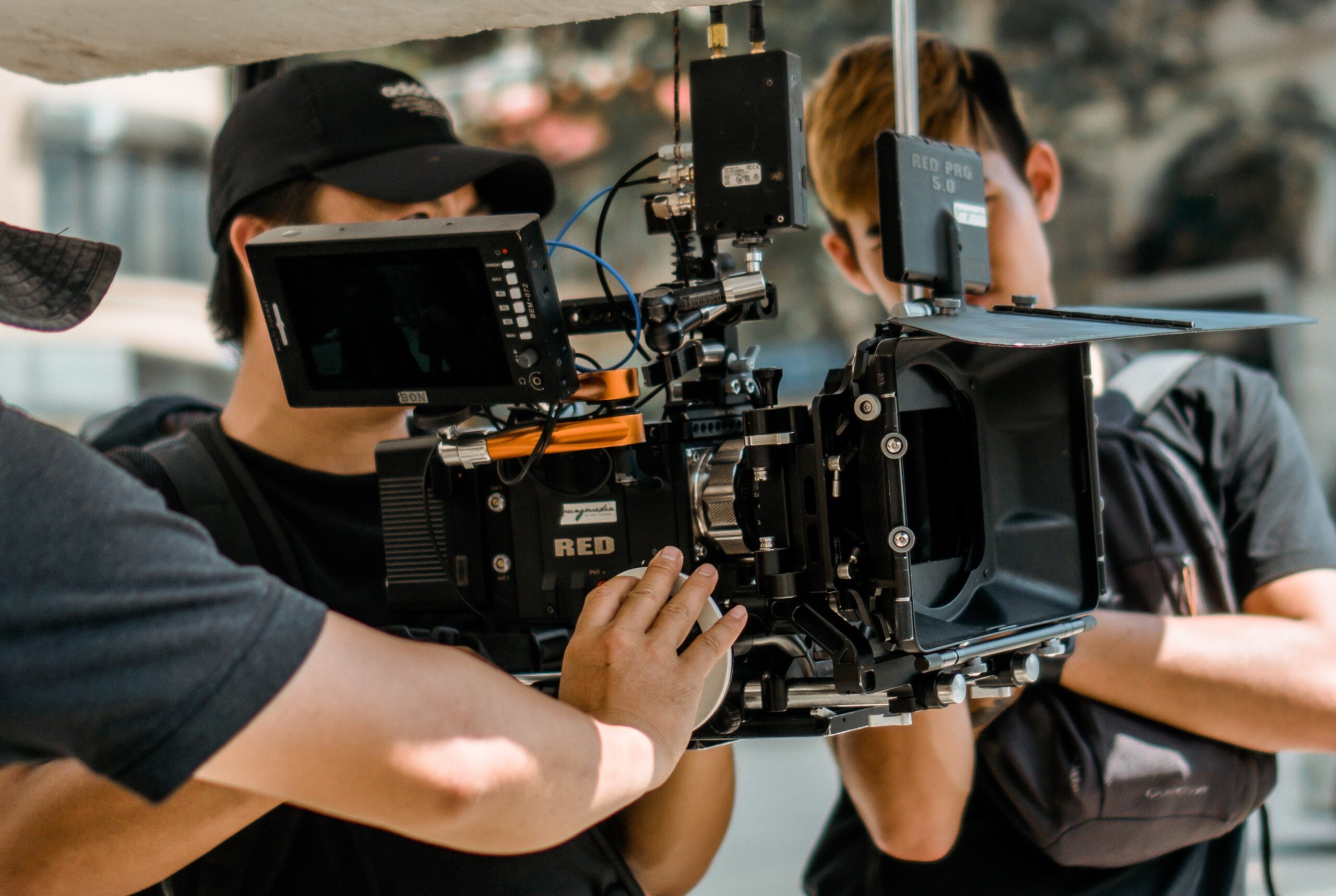 three men behind the camera filming - pexels.com