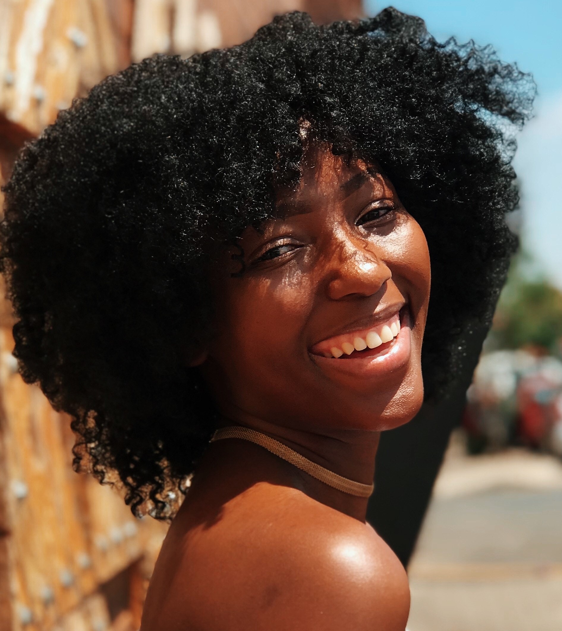 Black woman with think jet back hair, with a beautiful smile looking over her right shoulder