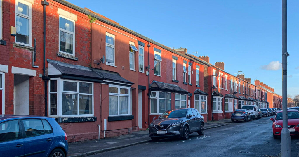 A row of terraced houses stretching into the distance. The weather is bright and sunny. There are no people in the picture.