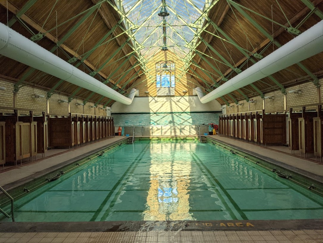 Withington Baths interior with pool and refurbished roof. Light reflects in pool water.