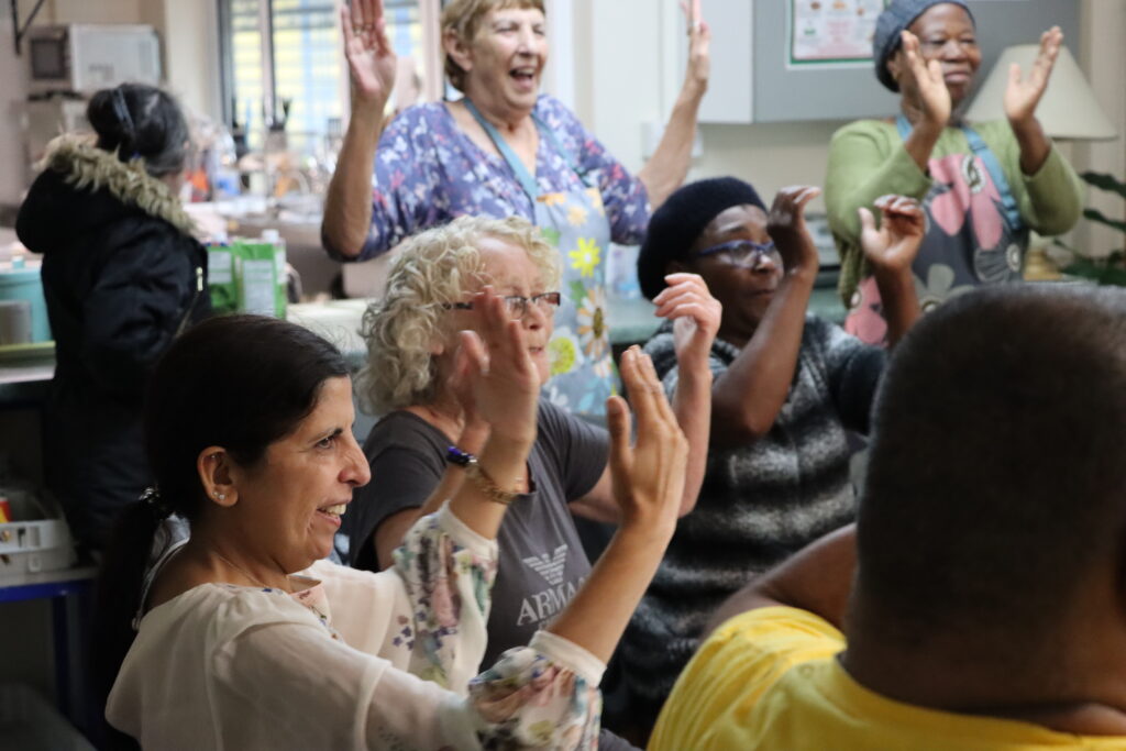 Multiple people sitting stretching arms in the air in exercise class.
