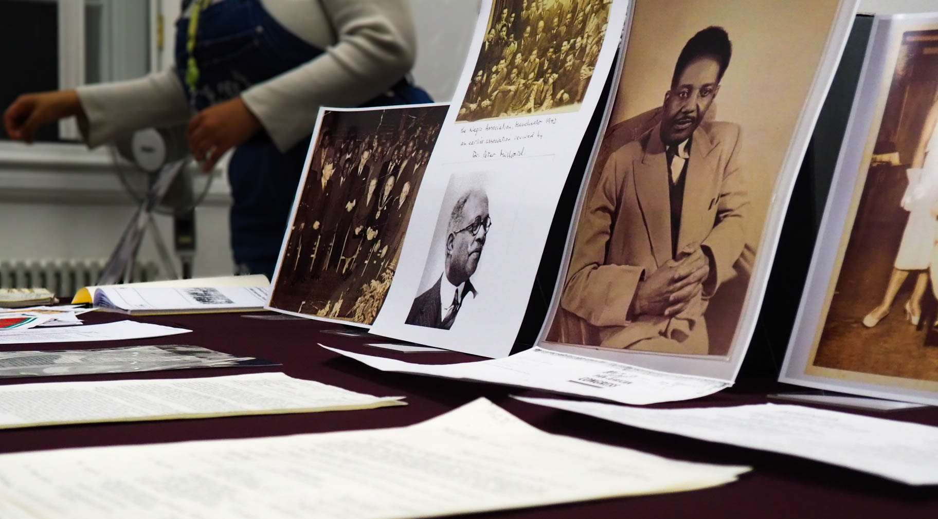 A spread of old sheets of typewritten paper in front of printed historical portraits propped up on a table.