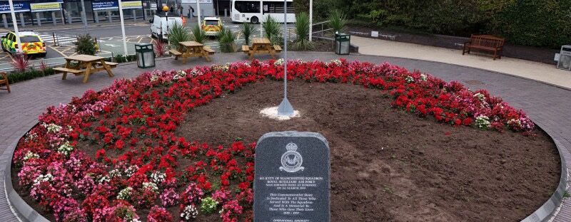 Memorial with a 1:4 scale spitfire over a circular flowerbed filled with poppies