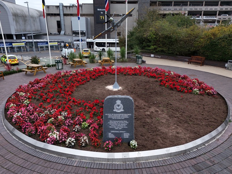 Memorial with a 1:4 scale spitfire over a circular flowerbed filled with poppies