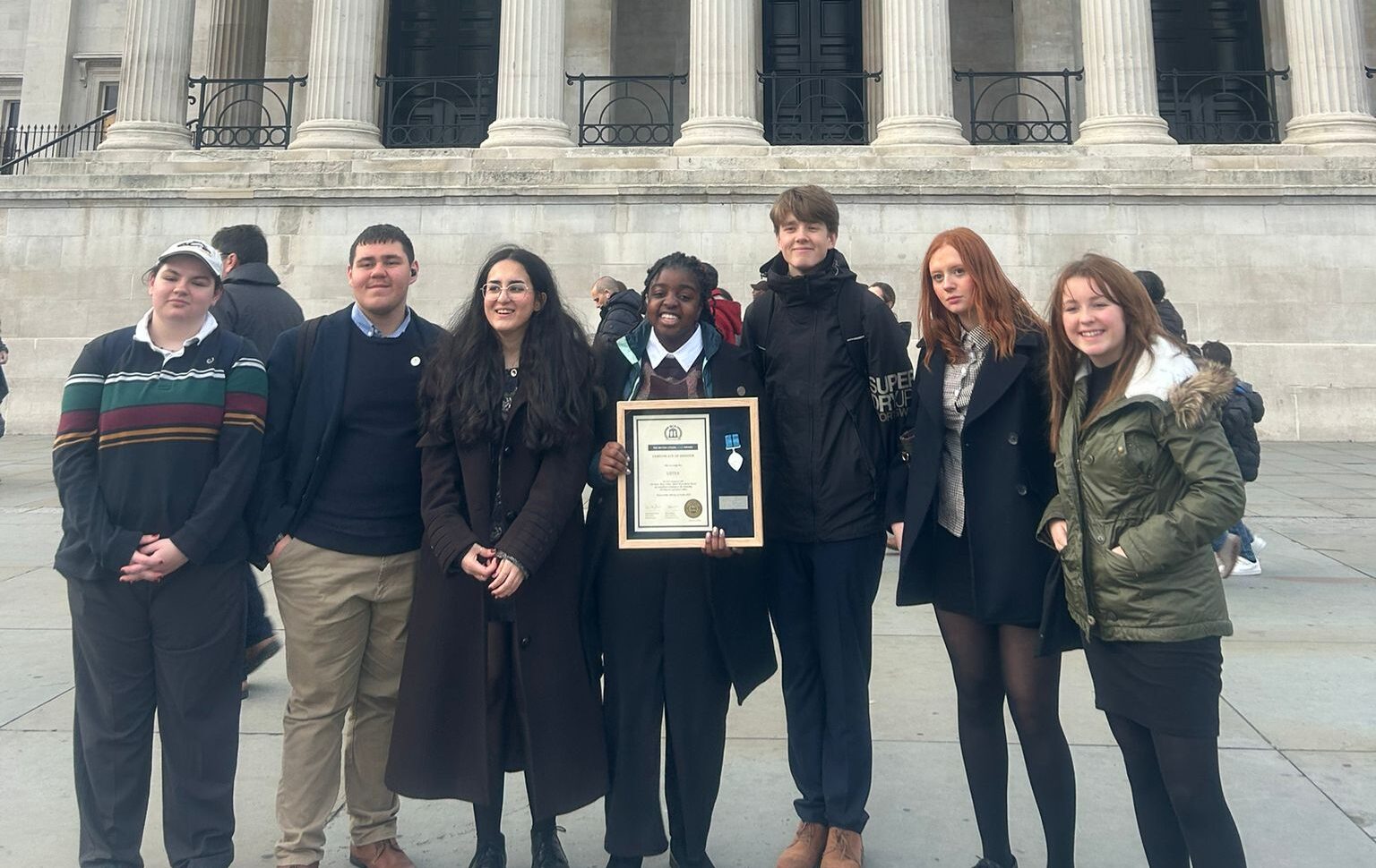 A group of people standing outside with an award