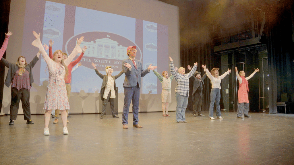 People stood on a stage with hands in the air

