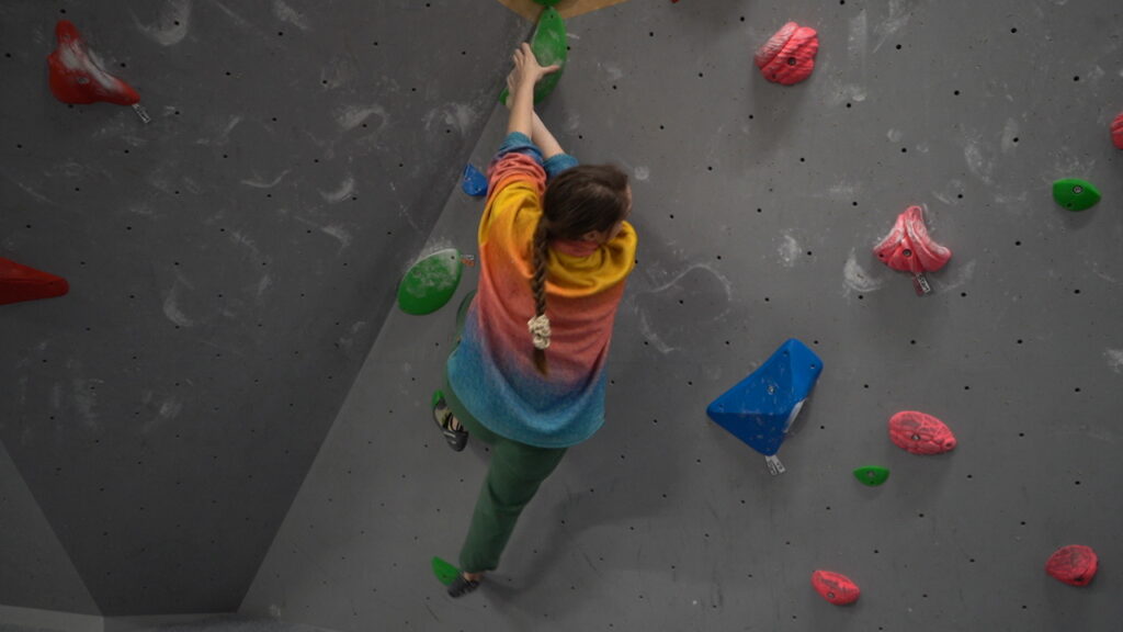 A female climber making her way up the boulder wall
